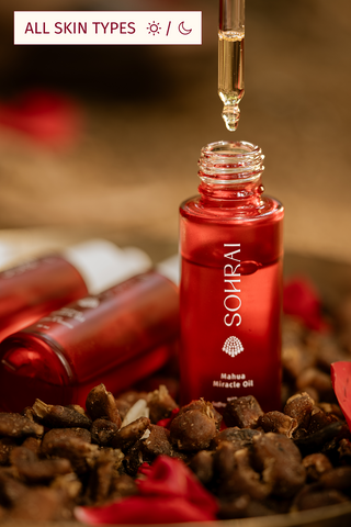 Red bottle of Sohrai Mahua Miracle Oil with a dropper on a textured surface.